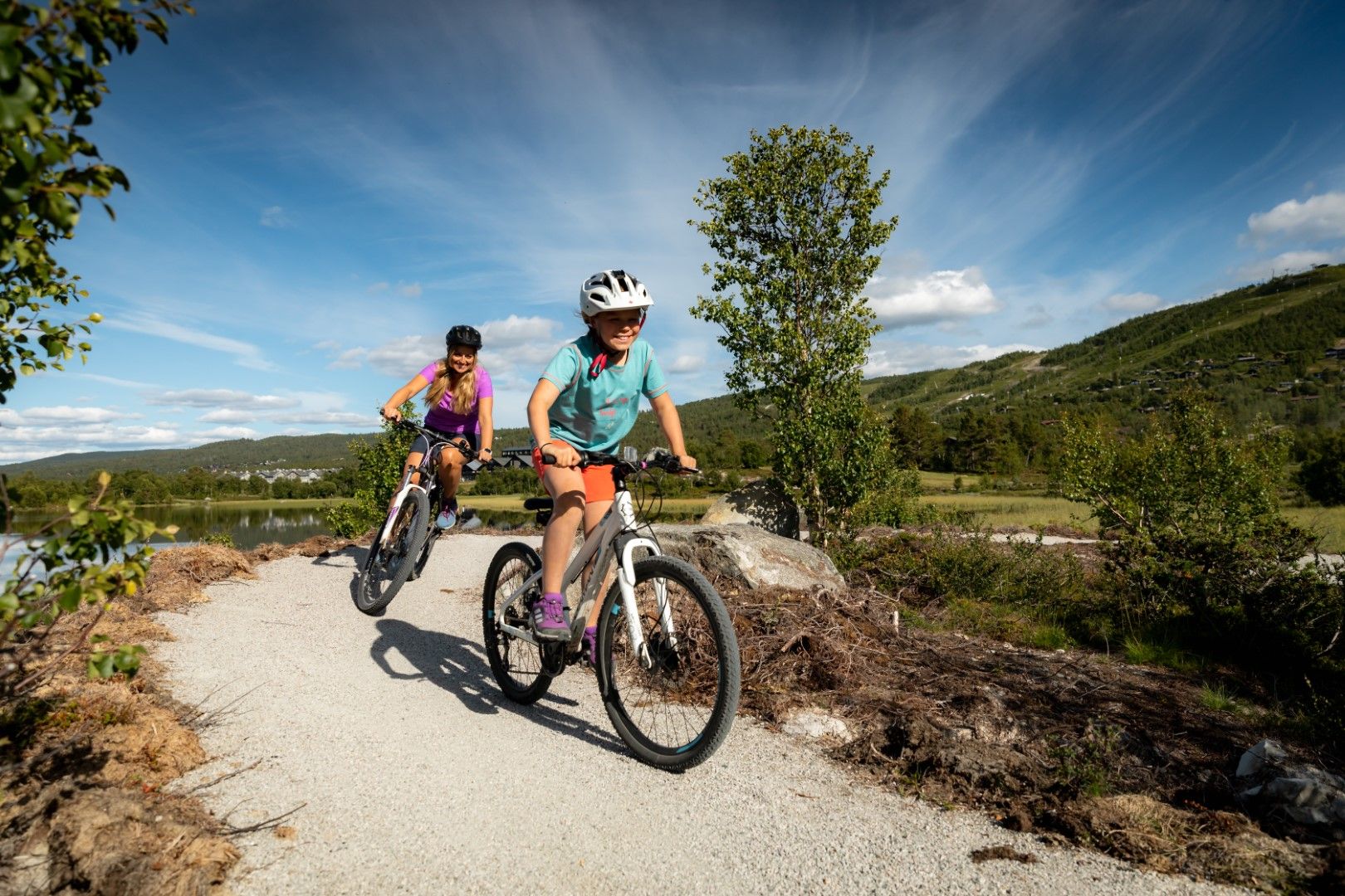 De jenter i sykkelparken ved et vann. Foto